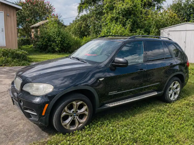 BMW X5 negra estacionada en una propiedad de Houston, disponible para venderse tal como está.